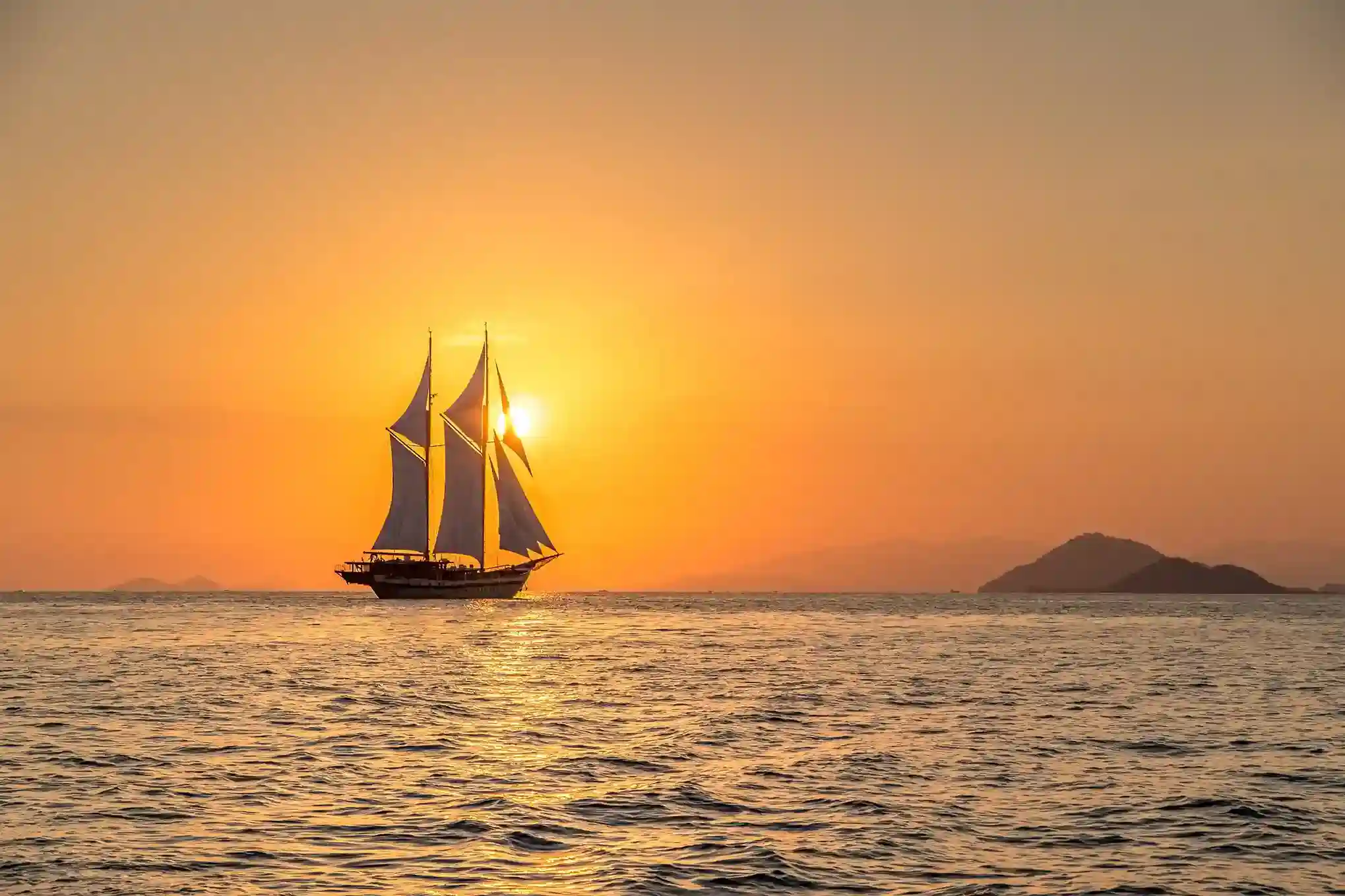 Phinisi silhouetted against a Flores Sea sunset